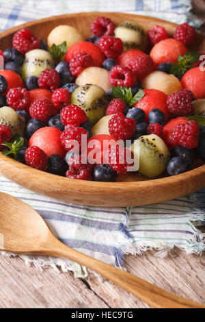Salat von frischen Früchten und Beeren in einer Holzschale Nahaufnahme. vertikalen rustikalen Stil Stockfoto