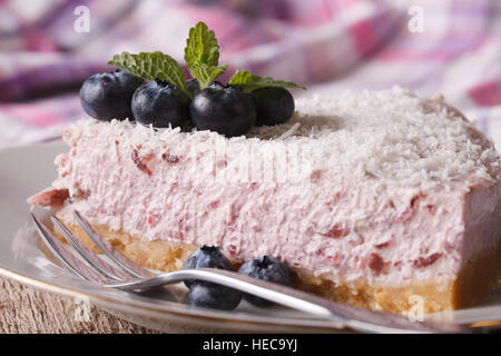 Ein Stück Blaubeer-Käsekuchen mit frischen Beeren und Kokosnuss Nahaufnahme auf einer Platte. horizontale Stockfoto