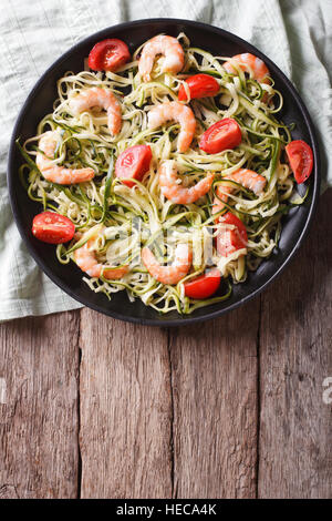 Zucchini-Nudeln mit Garnelen und Tomaten auf einem Teller. Vertikale Ansicht von oben Stockfoto