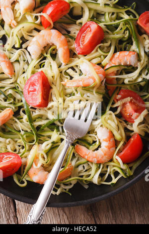 Zucchini Nudeln mit Garnelen und Tomaten auf einem Teller-Makro. Vertikale Ansicht von oben Stockfoto