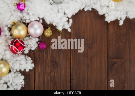 Farbigen Weihnachtskugeln und Schnee-Dekoration auf alten hölzernen Hintergrund Stockfoto