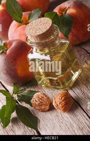 Natürliche Frische Pfirsich Öl in einer Glasflasche mit einer Tabelle Großaufnahme. vertikale Stockfoto