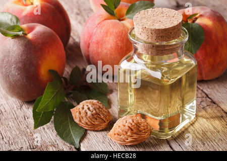 Kosmetisches Öl aus Kerne der Pfirsich in einer Glasflasche mit einer Tabelle Großaufnahme. horizontale Stockfoto