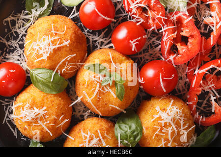 Italienisches Essen Hintergrund: frittierte Reisbällchen Arancini mit einem Salat aus frischem Gemüse Makro. horizontale Ansicht von oben Stockfoto