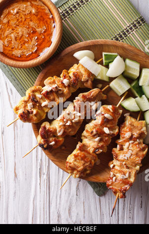 Chicken Satay mit einem leckeren Erdnuss-Sauce und frischem Salat auf der Platte Nahaufnahme. vertikale Ansicht von oben Stockfoto