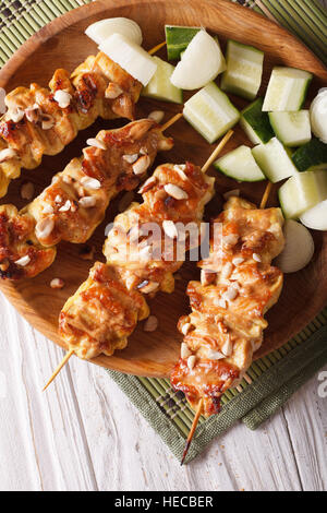 Chicken Satay bestreut mit Erdnüssen Nahaufnahme auf einer Platte. Vertikale Ansicht von oben Stockfoto