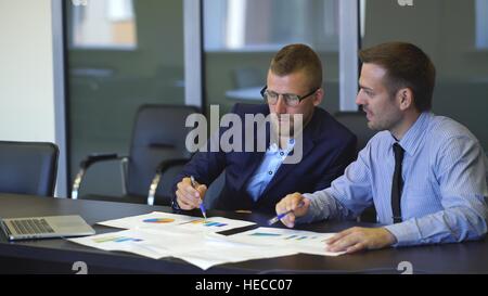 zwei Geschäftsleute in Gesprächen unter Berücksichtigung der Grafiken Stockfoto