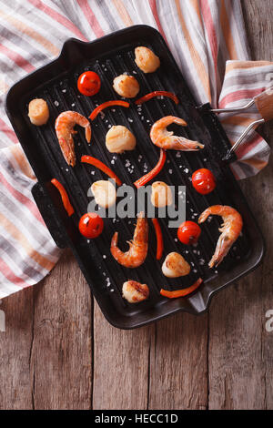 gegrillte Garnelen und Jakobsmuscheln auf dem Grill Pfanne auf dem Tisch. vertikale Ansicht von oben Stockfoto