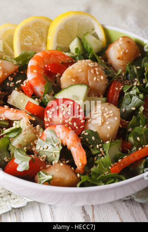 Salat mit Garnelen, Jakobsmuscheln und frischem Gemüse hautnah in eine Schüssel geben. Vertikal Stockfoto