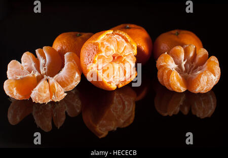 Gruppe von Mandarinen mit Spiegelbild auf schwarzem Hintergrund hautnah. Studiolicht. Stockfoto