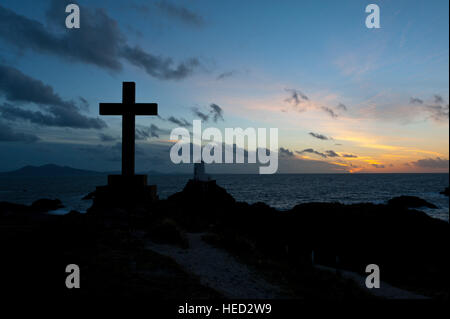 Newborough, Isle of Anglesey, Wales, UK. 21. Dezember 2016. Das Wetter.  St Dwynwens Cross und dem alten Leuchtturm sind am Abend der Wintersonnenwende der kürzeste Tag des Jahres 2016 gegen die untergehende Sonne auf Llanddwyn Island, aka Ynys Llanddwyn Silhouette. Das Wetter.  (Tageslicht) Daylength heute in London, UK werden 7 Stunden 49 Minuten 40 Sekunden. © Graham M. Lawrence/Alamy-Live-Nachrichten. Stockfoto