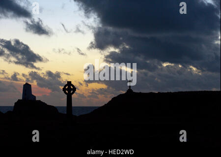 Newborough, Isle of Anglesey, Wales, UK. 21. Dezember 2016. Das Wetter.  Der alte Leuchtturm, einem keltischen Kreuz und St Dwynwens Cross sind Silhouette gegen die untergehende Sonne auf Llanddwyn Island, aka Ynys Llanddwyn am Abend der Wintersonnenwende der kürzeste Tag des Jahres 2016. Das Wetter.  (Tageslicht) Daylength heute in London, UK werden 7 Stunden 49 Minuten 40 Sekunden. © Graham M. Lawrence/Alamy-Live-Nachrichten. Stockfoto