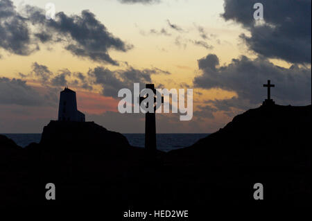 Newborough, Isle of Anglesey, Wales, UK. 21. Dezember 2016. Das Wetter.  Der alte Leuchtturm, einem keltischen Kreuz und St Dwynwens Cross sind Silhouette gegen die untergehende Sonne auf Llanddwyn Island, aka Ynys Llanddwyn am Abend der Wintersonnenwende der kürzeste Tag des Jahres 2016. Das Wetter.  (Tageslicht) Daylength heute in London, UK werden 7 Stunden 49 Minuten 40 Sekunden. © Graham M. Lawrence/Alamy-Live-Nachrichten. Stockfoto