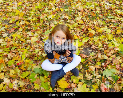 Mädchen sitzt auf der gelben Blätter im Herbst-park Stockfoto