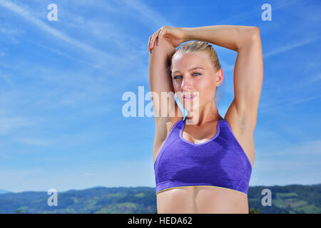 Junge Frau streckte ihre Arme bis während des Trainings auf einem Berg Stockfoto