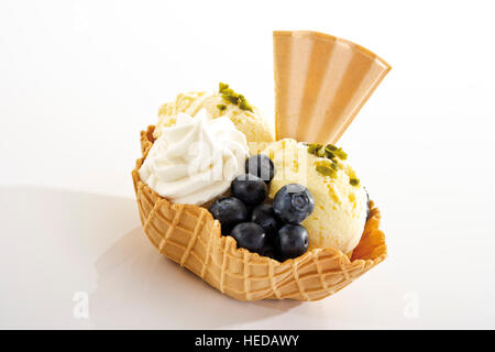 Vanilleeis, Heidelbeeren, Sahne und einem fächerförmigen Wafer in einer Wafer-Schüssel Stockfoto