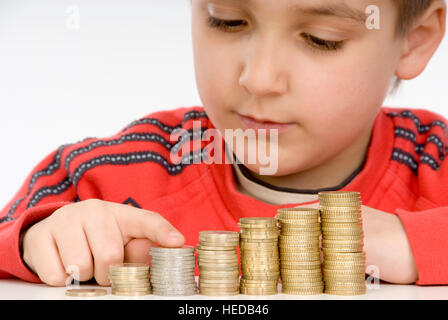 7-jähriger Junge zählen Stapel von Münzen, Münzen stapeln Stockfoto
