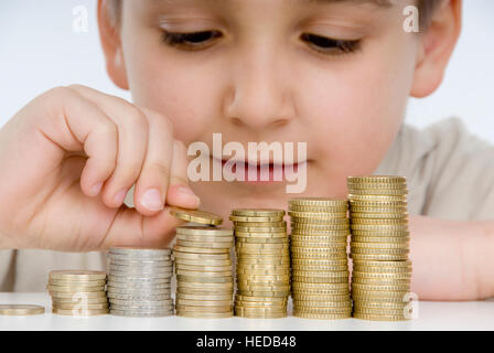 7-jähriger Junge zählen Stapel von Münzen, Münzen stapeln Stockfoto