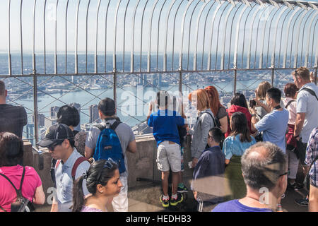 Touristen genießen die spektakuläre Aussicht von der großen Aussichtsplattform des Empire State Building. Stockfoto