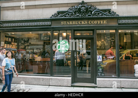 Eine Ladenzeile für einen Starbucks Coffee Shop-Standort in Manhattan mit Menschen zu Fuß durch und drinnen sitzen. Stockfoto