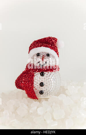 Schneemann auf einem Stapel von weißen kristallinen mit weißem Hintergrund. Stockfoto