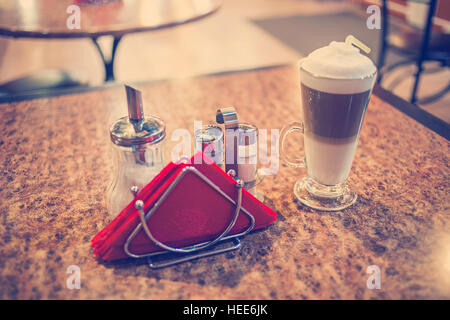 Kaffee Latte in einem Glas auf preshious Bubingo-Woood Tisch, eingefärbte Vintage Töne, flachen DOF, selektiven Fokus Stockfoto
