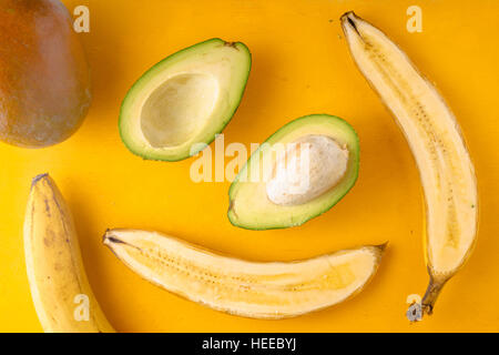 Bananen und Avocados auf einem gelben Hintergrund horizontale Stockfoto