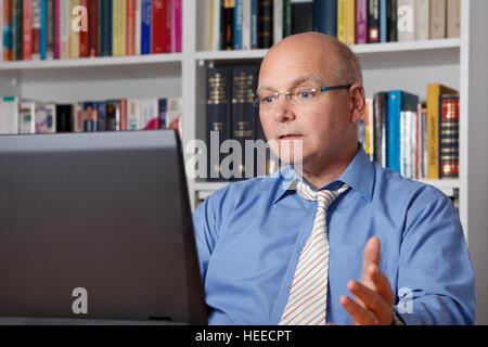 Verärgerter senior Mann in Hemd und Krawatte sitzen sehr ungeduldig und frustriert vor seinem Computer, Textfreiraum Stockfoto