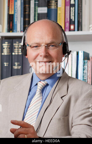 Älterer mann Hemd, Jacke, krawatte und Kopfhörer lächelt freundlich, Lehrer, Dozent, Professor, Übersetzer, Dolmetscher, Service Agent Stockfoto