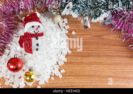 Schneemann auf einem Stapel von weißen kristallinen. Rote und gelbe Kugeln Weihnachtsschmuck auf Holz, Stockfoto