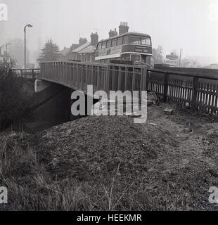 1965, historische, Bild zeigt neu erbaute Metall Fußgängerbrücke als Routemaster Bus Pässe über eine Straße Brücke, Aylesbury, England, UK. Stockfoto