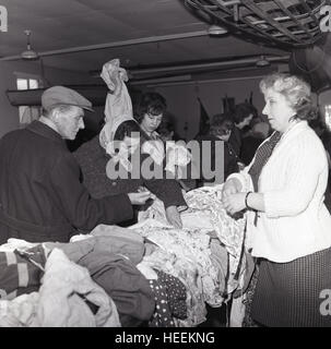 1965, historische, Menschen stöbern oder schauen Sie durch die second-hand-Kleidung finden Sie auf einen Stand auf einer Frauen Institut Flohmarkt. Stockfoto