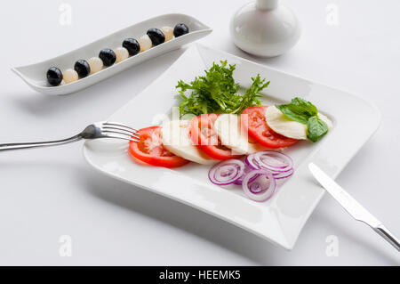 Eingerichtete Küche. Mozzarella-Käse-Salat mit Tomaten, schwarzen Oliven und Zwiebeln Stockfoto