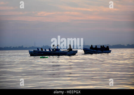 Reisende, die auf einem Boot in einem See in der Abenddämmerung Stockfoto