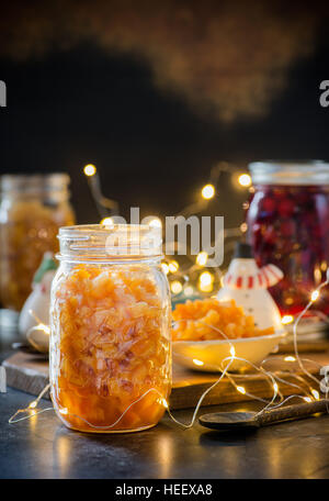 Hausgemachte Orangeat in Glas auf dunklem Hintergrund, festliche Lichter auf Rücken, Tiefenschärfe, Weihnachten Backzutat. Textfreiraum Stockfoto