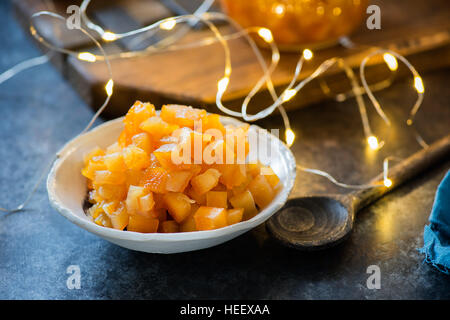 Hausgemachte Orangeat in Schüssel auf dunklem Hintergrund, festliche Lichter auf Rücken, Tiefenschärfe, Weihnachten Backzutat Stockfoto