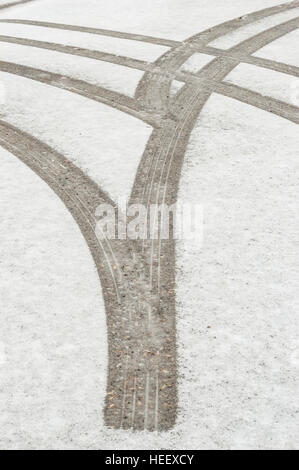 Reifenspuren / Markierungen im Neuschnee auf einer asphaltierten Straße. Stockfoto