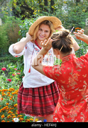 zwei Mädchen im Teenageralter in traditionellen ukrainischen und chinesische Kleidung in der Sommerlandschaft Stockfoto