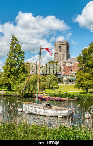 Segelschiff auf dem Fluß Frome in der Nähe von Wareham mit der Lady Maria-Kirche im Hintergrund, Dorset, South East England. Stockfoto