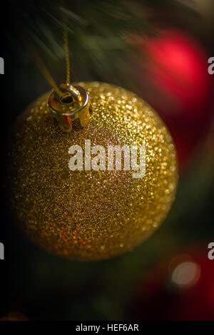 Rote und goldene Kugeln heben sich gegen die Lichter am Weihnachtsbaum. Stockfoto