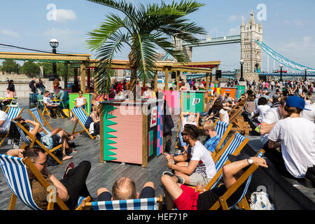 Eine temporäre Sommerbar und Strand eingerichtet am südlichen Ufer der Themse mit Menschen und Tower Bridge, London, UK. Stockfoto