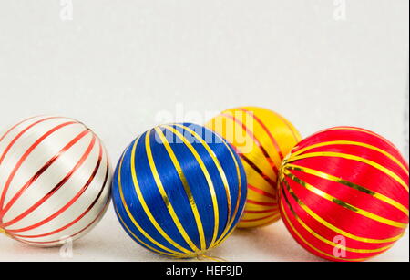 drei bunte Weihnachtskugeln mit goldenen Linien auf weißem Stockfoto