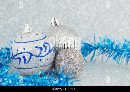 drei silberne Weihnachtskugeln mit glänzenden blauen Band Stockfoto