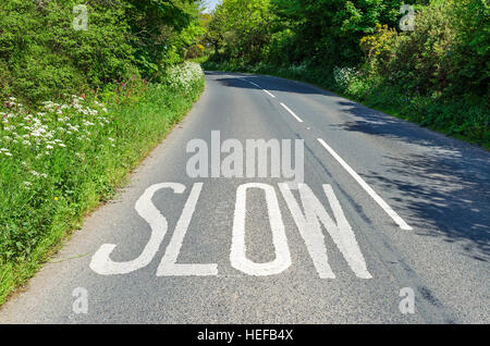 Ein langsamen Zeichen gemalt auf einer Landstraße in England, UK Stockfoto