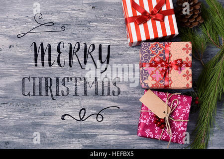 High-Angle Shot von einigen gemütlichen Geschenken in verschiedene schöne Papiere gewickelt und gebunden mit Bändern und Strings in verschiedenen Farben und den Text frohe Weihnac Stockfoto