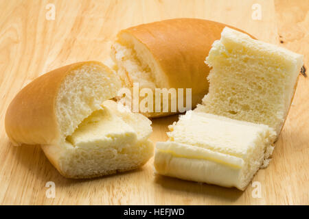 Hotdog Brot gefüllt mit gesüßter Buttercreme auf einem Holzbrett Stockfoto