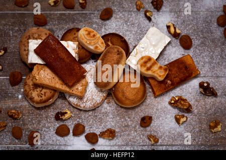 High-Angle Shot von einem rustikalen Holztisch voller Mandeln und Kastanien und ein Haufen andere typische Weihnachtsgebäck in Spanien, wie z. B. Turron, Mann Stockfoto