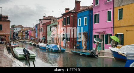 Bunte Häuser durch Kanal mit Motorbooten während Regen, Burano, Venedig, Veneto, Italien Stockfoto