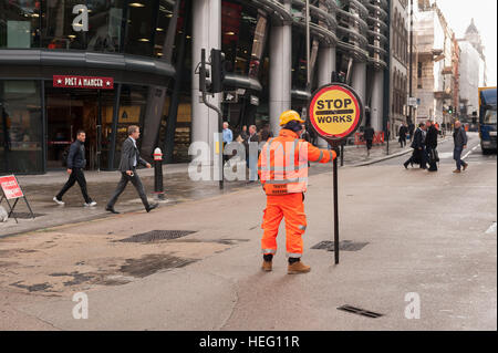 Hochsichtbare Bekleidung Arbeiter steuert manuell Verkehr und Fußgänger außerhalb der Kanone-Straße Hauptstraße Stockfoto