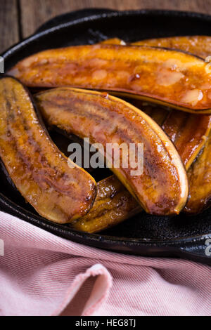 Hausgemachte karamellisierte Banane in Gusseisen Pfanne auf hölzernen rustikalen Pfanne, Vegan dessert Stockfoto